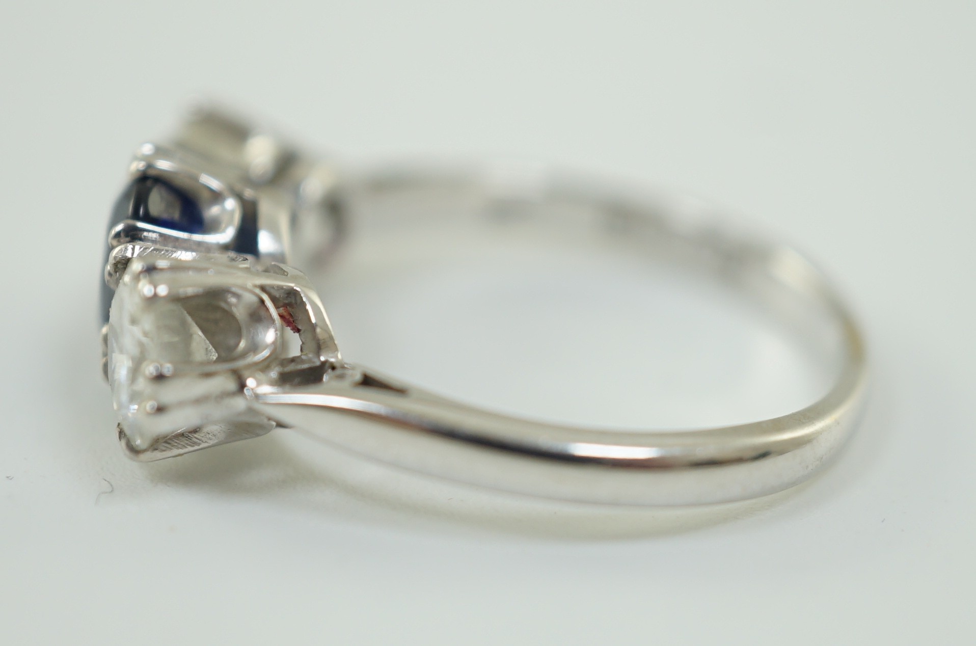 A modern 18ct white gold, single stone oval cut sapphire and two stone round cut diamond set ring